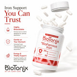 Tilted BioTonix BioFerrous Iron bottle spilling white capsules showing key benefits like high absorption, gentle digestion, and energy support.
