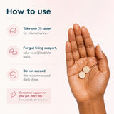Open hand holding two BioTonix BioGut Restore tablets next to daily dosage directions for maintenance and gut lining support