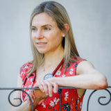 Dr. Terry Ann wearing a red floral blouse and stethoscope leaning on a balcony railing.