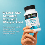 Hand holding Naturmade Charco Tabs bottle displaying 125mg C-Extra USP activated charcoal detail.
