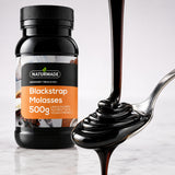 Dark Naturmade Blackstrap Molasses pouring smoothly onto a spoon with product container in background