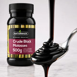 Thick dark Naturmade Crude Black Molasses pouring onto a spoon with product bottle in background
